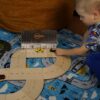 Boy playing with natural plywood toy road with model cars